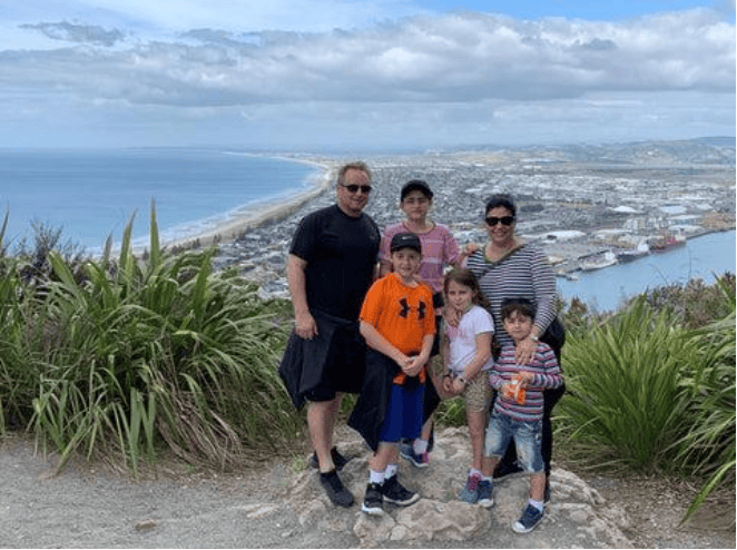 Family of six poses for a photo overlooking a coastal town.
